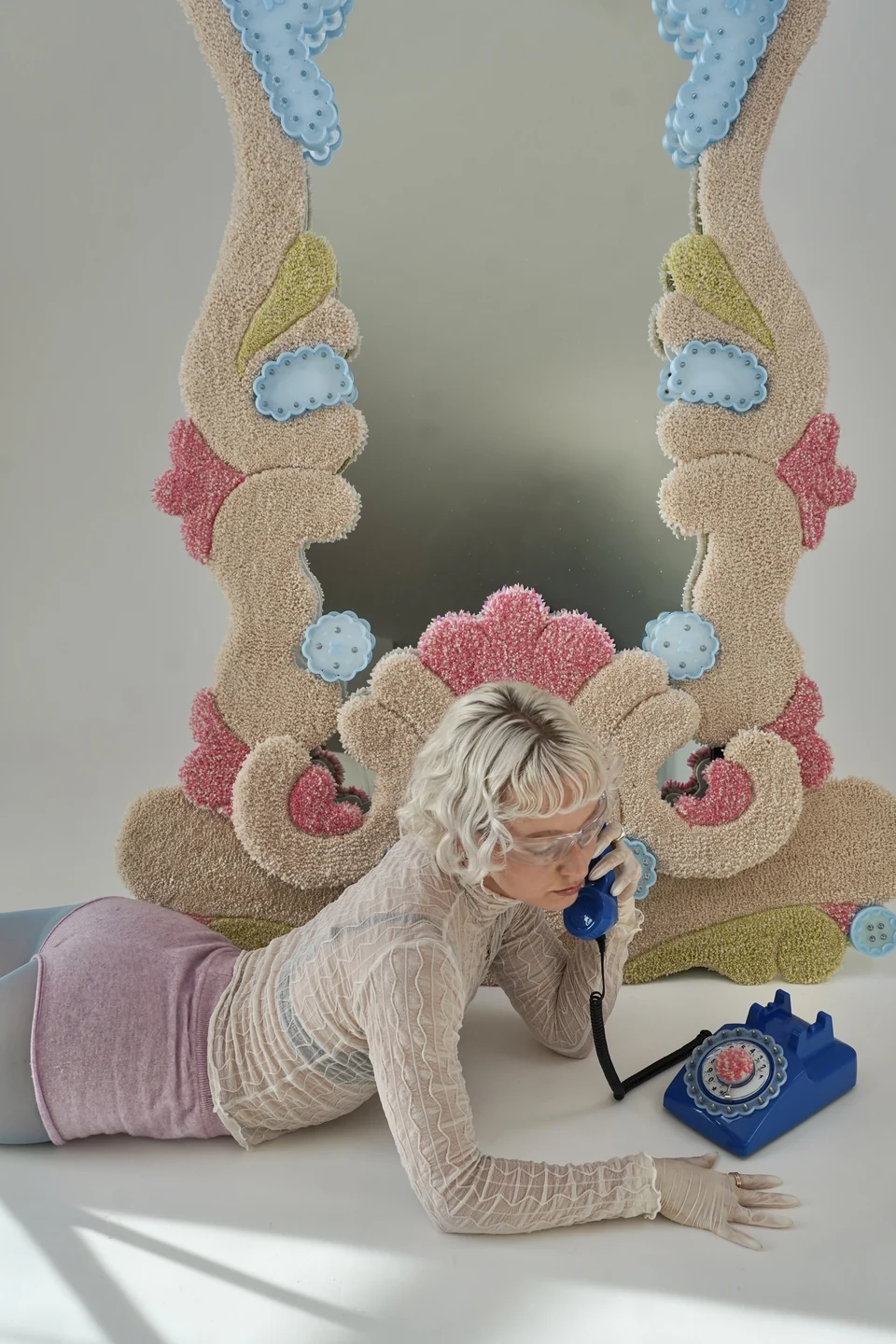 Nadia, the artist and designer behind Poster Therapy Lab, with her tufted Receiver mirror and blue telephone.